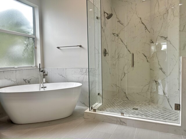 bathroom with plus walk in shower, tile patterned floors, and tile walls