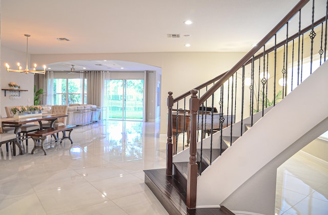 stairway featuring light tile patterned flooring and an inviting chandelier