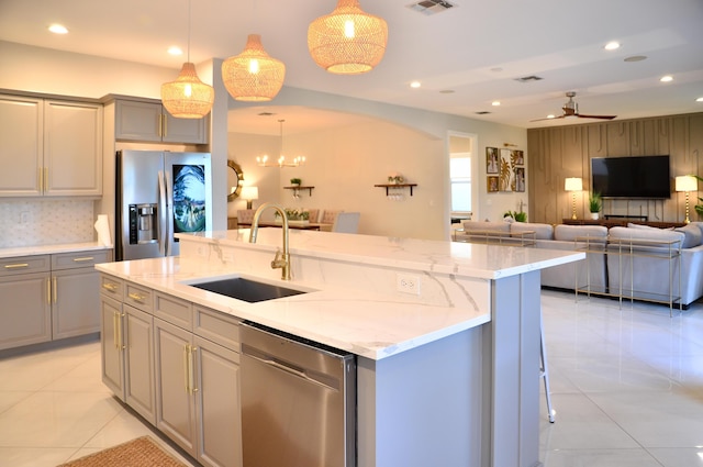 kitchen with sink, gray cabinetry, hanging light fixtures, stainless steel appliances, and an island with sink