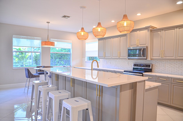 kitchen with stainless steel appliances, a kitchen island, light tile patterned floors, backsplash, and gray cabinetry