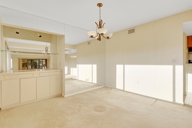 unfurnished living room with light colored carpet and a chandelier