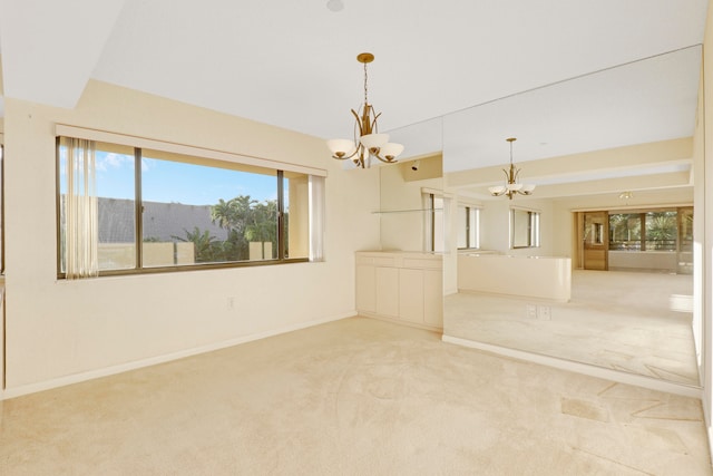 carpeted spare room with an inviting chandelier