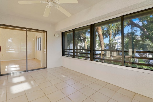 unfurnished sunroom featuring a healthy amount of sunlight and ceiling fan