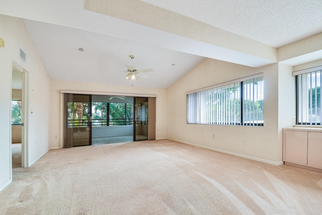 empty room featuring lofted ceiling, a healthy amount of sunlight, light carpet, and ceiling fan