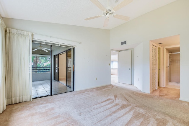 unfurnished bedroom featuring access to exterior, ceiling fan, light colored carpet, vaulted ceiling, and a closet