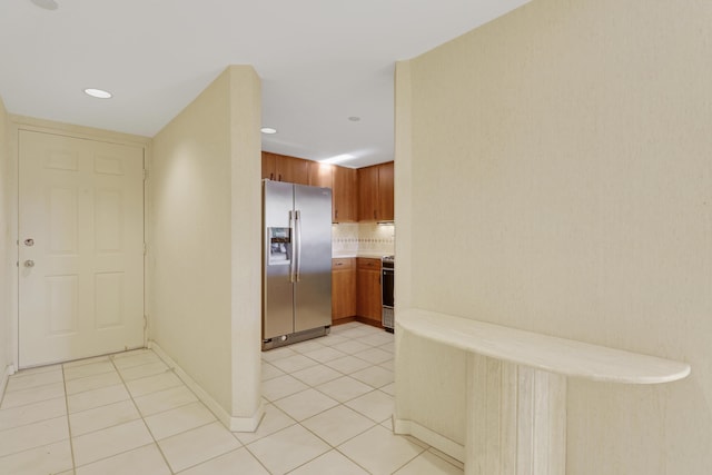 kitchen featuring stove, light tile patterned floors, and stainless steel fridge