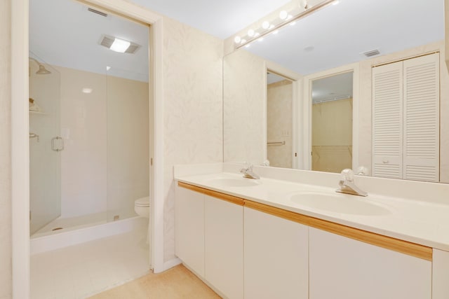 bathroom with a shower with shower door, toilet, and double vanity