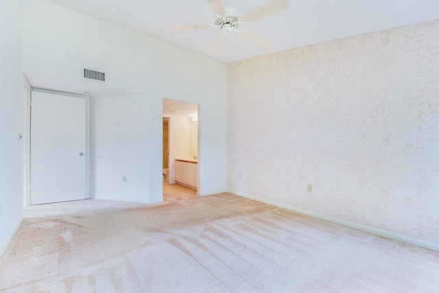 unfurnished bedroom with ensuite bath, ceiling fan, and light colored carpet