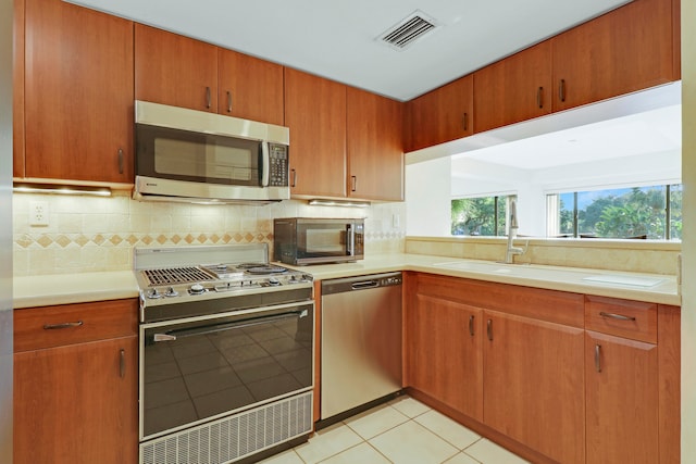 kitchen with decorative backsplash, sink, appliances with stainless steel finishes, and light tile patterned floors