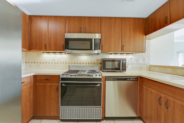 kitchen with light tile patterned floors, tasteful backsplash, and stainless steel appliances