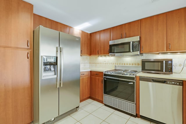 kitchen with stainless steel appliances, backsplash, and light tile patterned floors