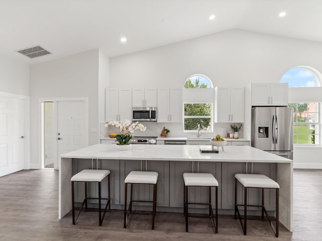 kitchen featuring white cabinetry, dark hardwood / wood-style floors, appliances with stainless steel finishes, a spacious island, and plenty of natural light