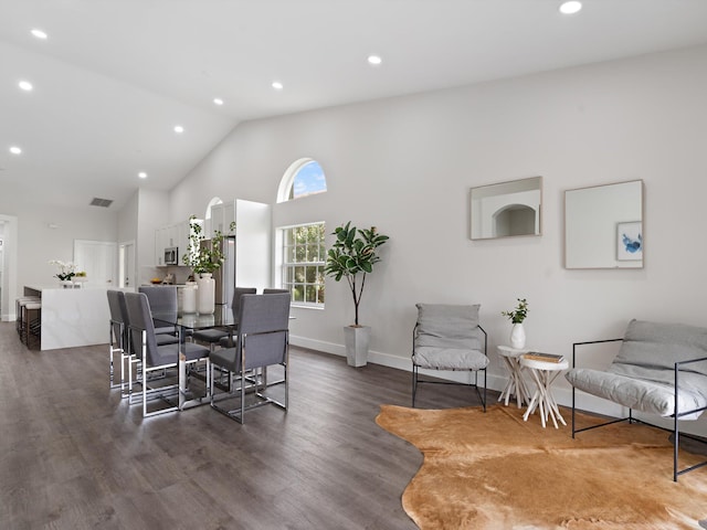 dining room with high vaulted ceiling and dark hardwood / wood-style floors