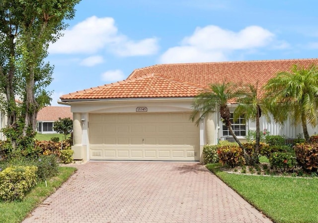 mediterranean / spanish home featuring a tile roof, decorative driveway, a garage, and stucco siding