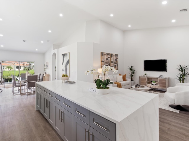 kitchen featuring a center island, gray cabinetry, light stone counters, and light hardwood / wood-style floors