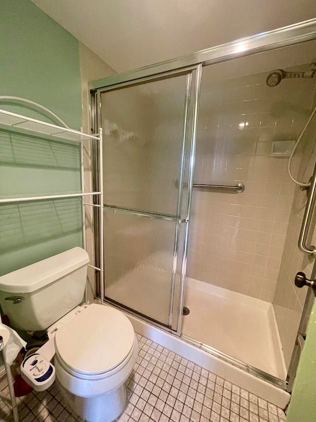 bathroom featuring tile patterned floors, toilet, and an enclosed shower