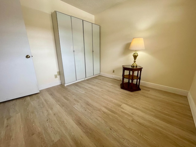 unfurnished bedroom with a textured ceiling, light hardwood / wood-style flooring, and a closet