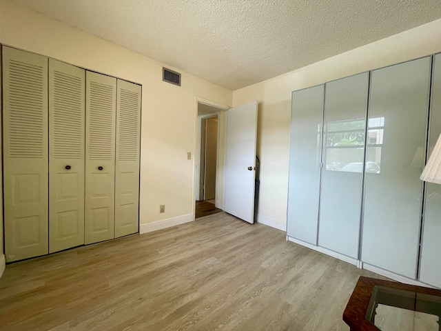 unfurnished bedroom with a textured ceiling and light hardwood / wood-style flooring