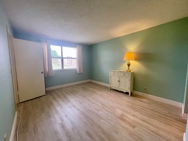 empty room with light hardwood / wood-style floors and a textured ceiling