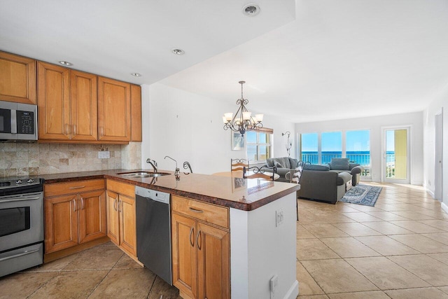 kitchen with kitchen peninsula, appliances with stainless steel finishes, backsplash, sink, and a chandelier