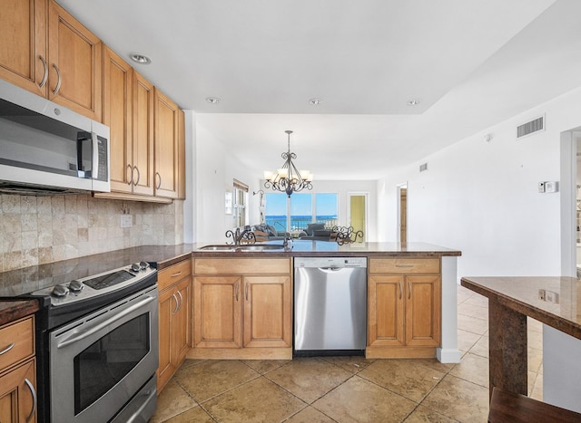 kitchen with sink, light tile patterned floors, a notable chandelier, kitchen peninsula, and stainless steel appliances