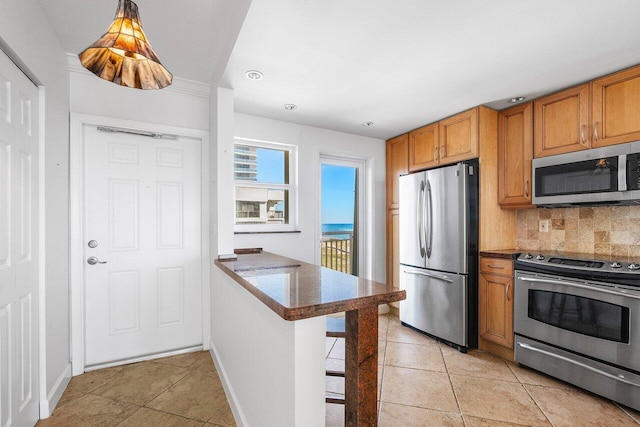 kitchen featuring kitchen peninsula, appliances with stainless steel finishes, backsplash, a breakfast bar, and light tile patterned floors