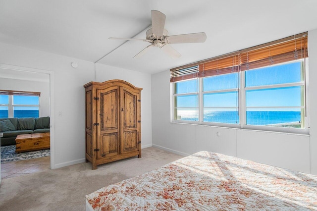 bedroom featuring ceiling fan, a water view, and light carpet