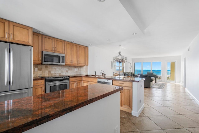 kitchen with kitchen peninsula, backsplash, appliances with stainless steel finishes, and an inviting chandelier