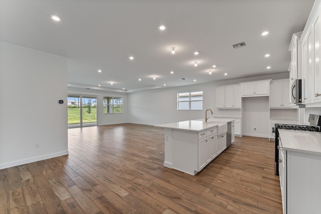 kitchen featuring white cabinets, a kitchen island with sink, appliances with stainless steel finishes, hardwood / wood-style floors, and sink