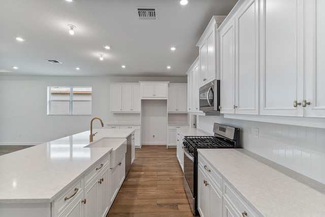 kitchen featuring white cabinetry, an island with sink, appliances with stainless steel finishes, wood-type flooring, and sink