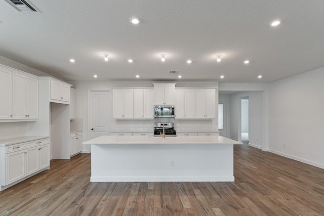 kitchen with appliances with stainless steel finishes, wood-type flooring, and an island with sink