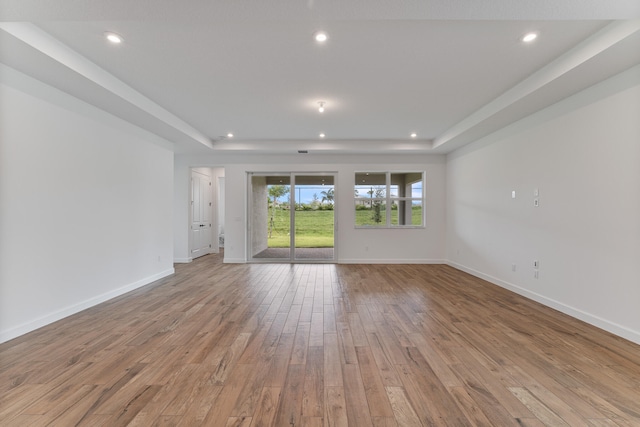 unfurnished living room with a tray ceiling and hardwood / wood-style flooring