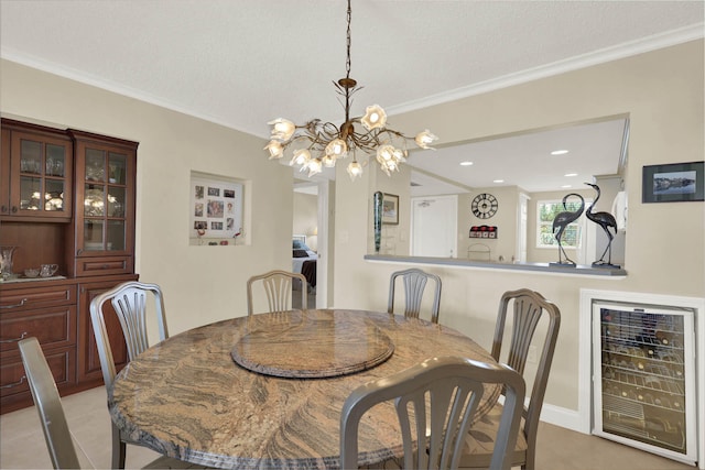 dining space featuring beverage cooler, a textured ceiling, ornamental molding, and an inviting chandelier