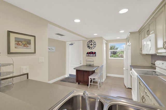 kitchen with sink, cream cabinets, light tile patterned floors, and white appliances