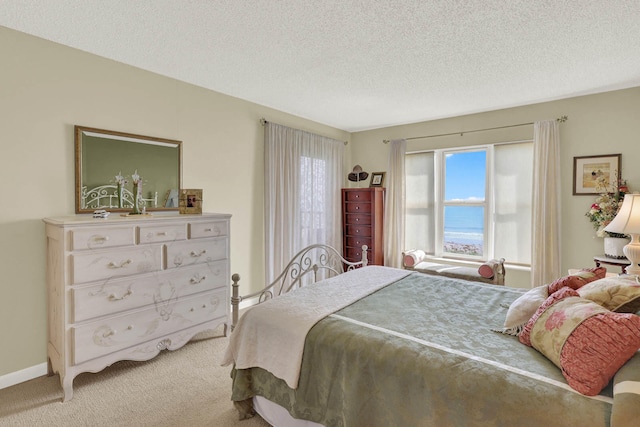 bedroom with a water view, carpet, and a textured ceiling