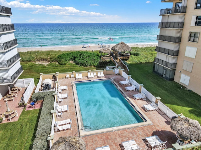 view of swimming pool with a water view, a patio area, and a lawn