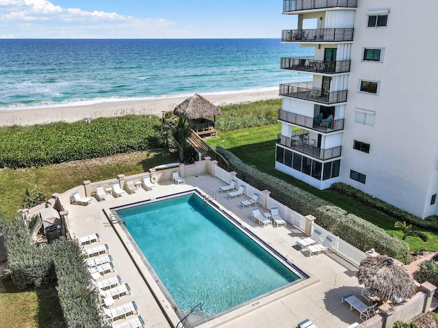 view of pool featuring a beach view, a water view, and a patio