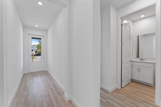 corridor with sink and light wood-type flooring