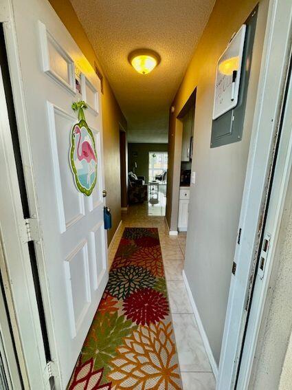 hallway with light tile patterned floors and a textured ceiling