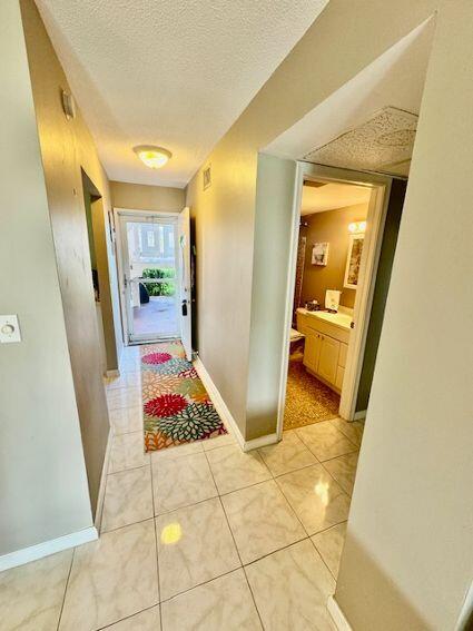 hall with a textured ceiling and light tile patterned floors