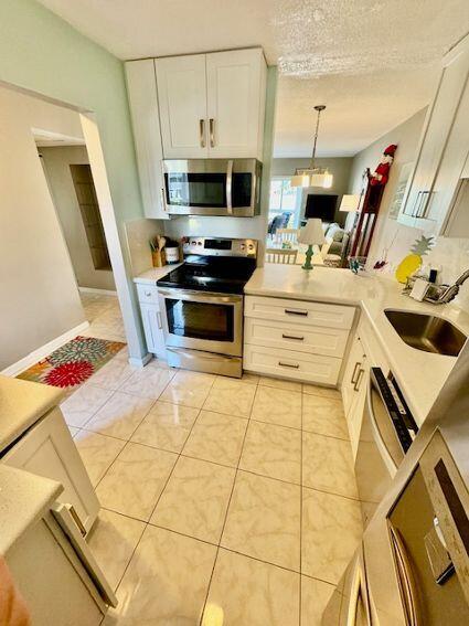 kitchen with white cabinets, sink, light tile patterned flooring, and stainless steel appliances