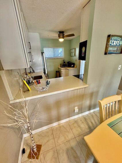 kitchen featuring light tile patterned flooring, sink, a textured ceiling, ceiling fan, and white cabinets