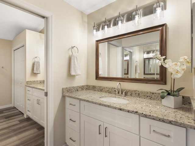 6166 Lake Hibiscus Dr, Delray Beach, FL 33484 - bathroom featuring vanity, wood finished floors, and baseboards
