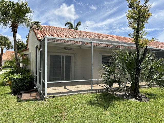 rear view of house featuring a lawn and ceiling fan