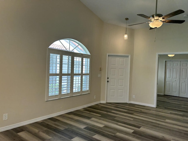 interior space with a high ceiling, ceiling fan, and dark hardwood / wood-style flooring