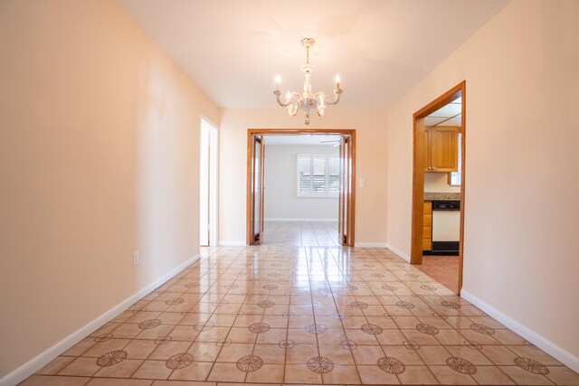 spare room with an inviting chandelier and light tile patterned flooring