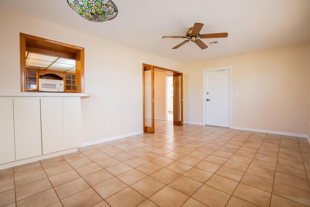 tiled empty room featuring ceiling fan