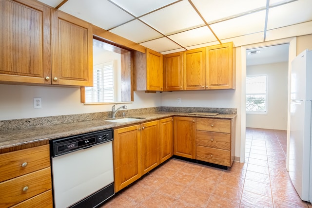 kitchen with light tile patterned floors, white appliances, stone countertops, and sink