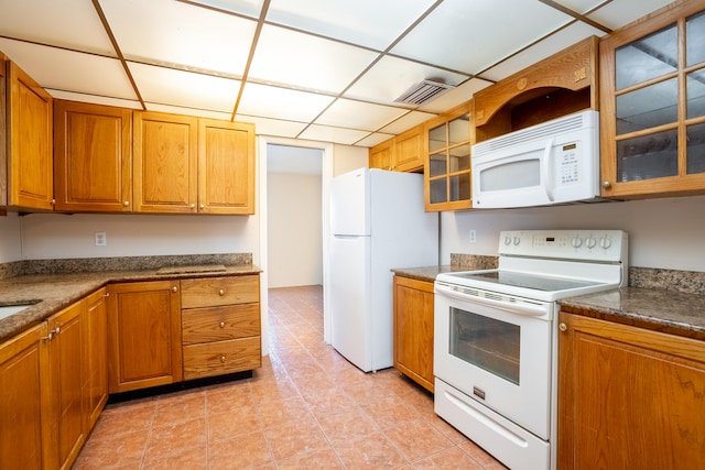 kitchen with a paneled ceiling, white appliances, and light tile patterned floors