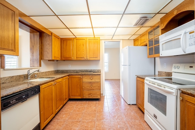 kitchen with a healthy amount of sunlight, white appliances, light tile patterned flooring, and sink